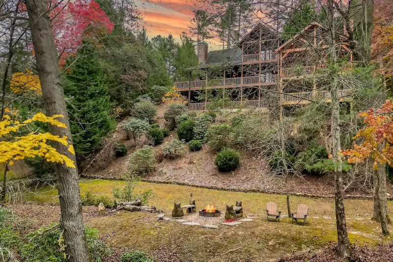 Trout Tales Riverfront Lodge above a wooded yard and fire pit in Ellijay