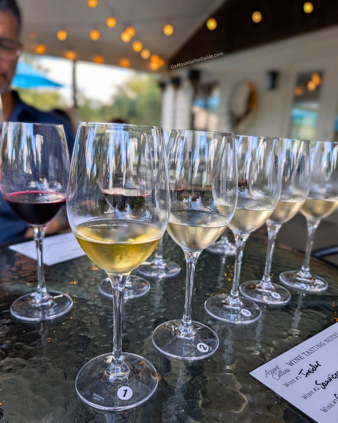 Red and white wine tasting glasses on a covered patio table at Accent Cellars in Dahlonega